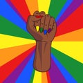 Black skinned female pride fist with lgbt rainbow colored finger nails and rainbow rays in background. Sign for gender equality